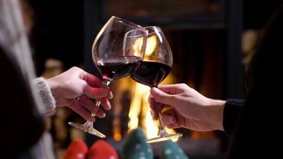 一个冬天的晚上一对夫妇坐在壁炉前放松一边喝着一杯葡萄酒一边敬酒享受着壁炉的温暖概念:度假、休闲、红酒