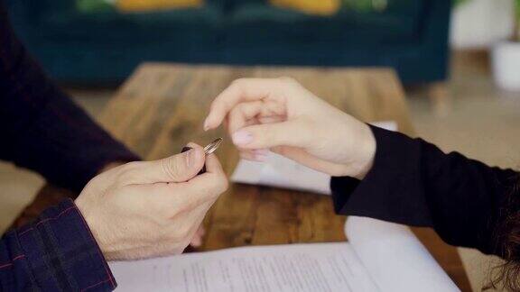 男子手签买卖合同从房产中介手里拿到房子钥匙然后握手的特写房地产买卖概念
