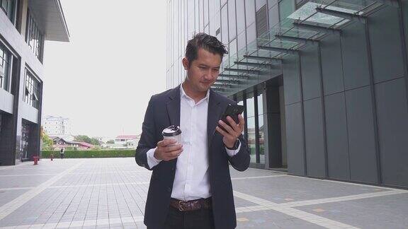 亚洲年轻聪明的商人在城市里打电话男人站在外面喝着咖啡面带微笑地去办公室工作