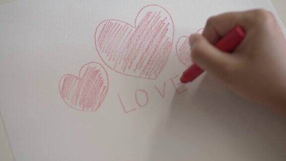 女人用蜡笔在白纸上写下了一个红心图案的“爱”字