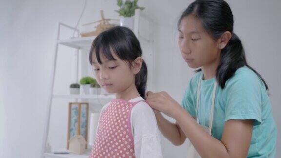 亚洲姐姐帮姐姐穿上围裙在家里一起烘焙生活理念