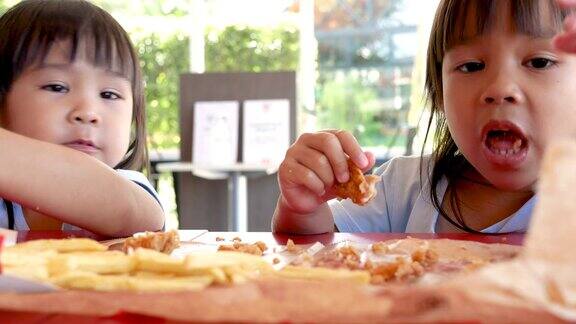 快乐的亚洲姐妹喜欢在服务店吃炸鸡和炸薯条垃圾食品和健康概念