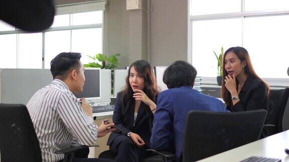 年轻的亚洲商业团体聊天八卦老板在办公室玩得很开心