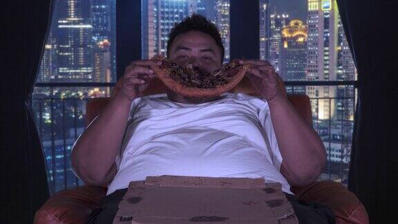 超重男子在公寓里吃大披萨