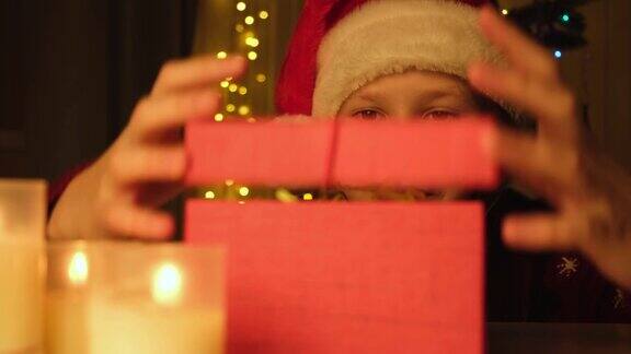 戴圣诞帽的小女孩打开红色的圣诞礼盒惊喜地看着里面圣诞快乐