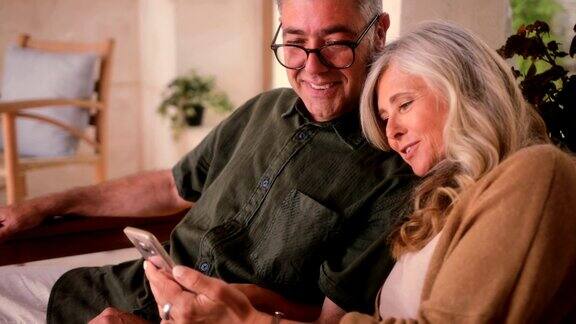 幸福的成熟夫妇使用智能手机在家里一起放松