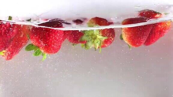 高清:慢动作草莓掉进水里白色背景慢动作
