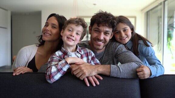 美丽的拉丁美洲家庭两个孩子坐在沙发上对着镜头微笑非常开心