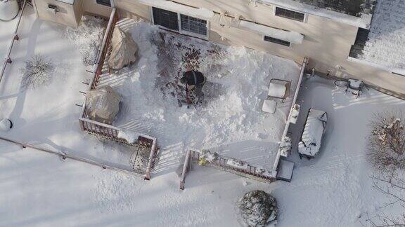 一个成年人在冬天下雪后用铲子清理门廊上的积雪鸟瞰图直接上方的无人机慢动作视频