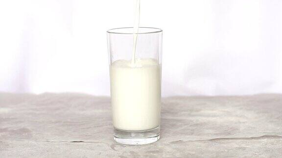 牛奶被慢慢地倒在一杯白色的背景上