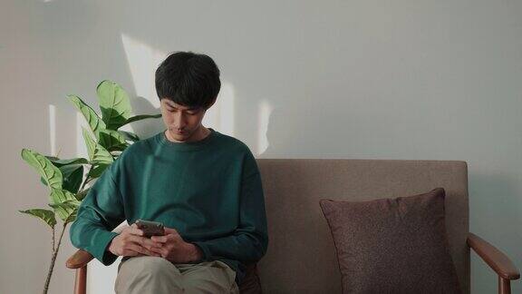 亚洲男人在沙发上使用智能手机