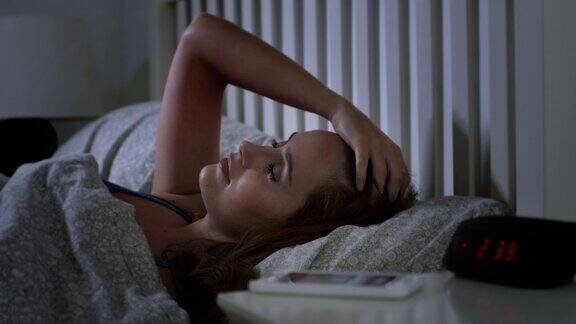 因为电话留言而醒来年轻女子躺在床上被手机吵醒了