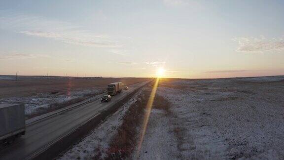 黎明时分几辆卡车和轿车在雪地上的草原上驶过