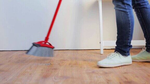 在家里用扫帚清扫地板的妇女