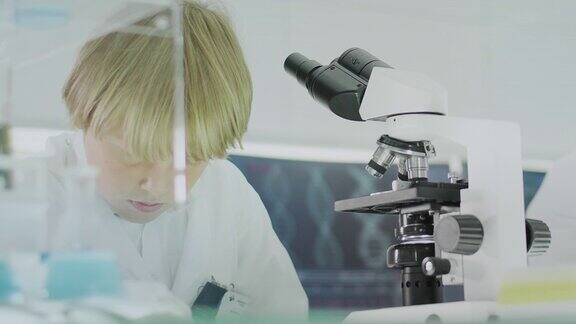 忙碌的男孩在现代实验室使用显微镜近距离观察面部
