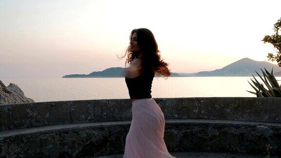 年轻女子晚上在海边的篱笆旁跳舞