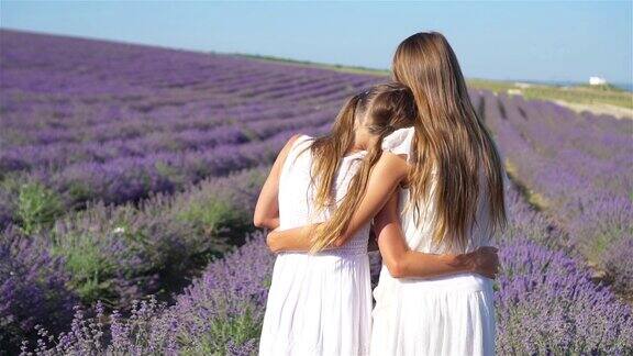 日落时分女孩们穿着白色的连衣裙站在薰衣草花丛中