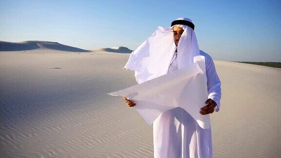 在炎热的夏日站在广阔的沙漠中认真的年轻阿拉伯阿联酋商人谢赫正在考虑建设计划