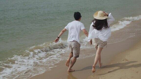 年轻的亚洲夫妇在爱牵手和奔跑在海滩上愉快的幸福假期周末白人夫妇幸福的微笑浪漫在海边玩得开心