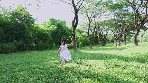 亚洲的小女孩和父亲带着风筝在夏季的草地上奔跑和快乐的大自然中慢镜头