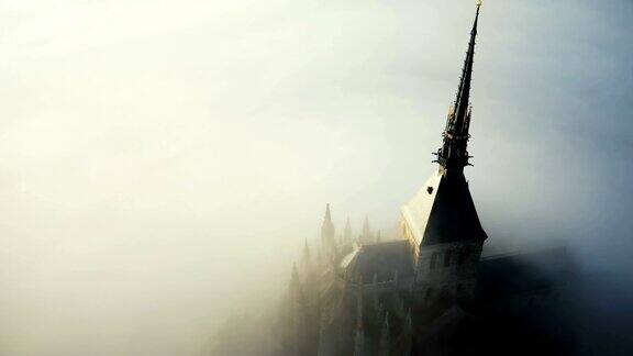 无人机在诺曼底圣米歇尔山顶的阳光明媚的哥特式修道院建筑周围飞行