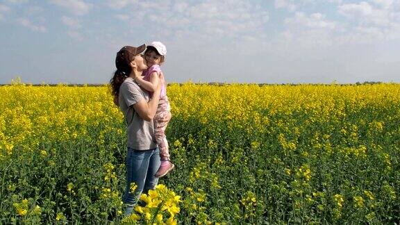 母亲拥抱她的女儿在大自然中黄色田野上的女人和小女孩一个幸福的家庭