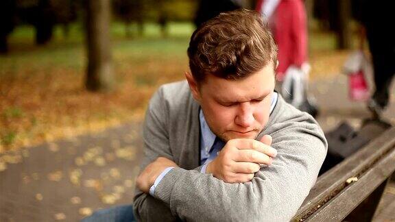 沮丧悲伤的年轻商人坐在公园里