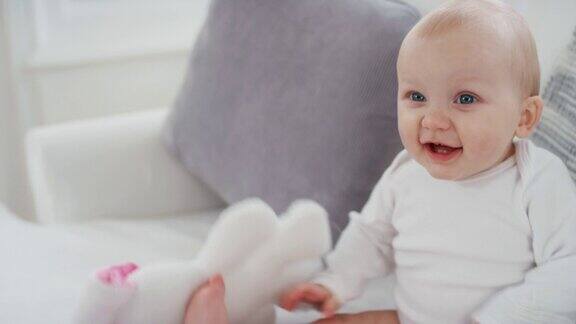 肖像快乐的婴儿与美丽的蓝眼睛看着好奇的蹒跚学步微笑享受生活健康的小婴儿在家里4k