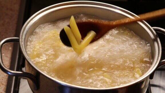 用木勺在沸水中搅拌意大利面