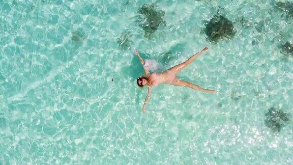 一个女人在海洋上漂浮和游泳的无人机视图