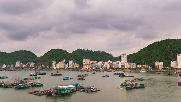 时间流逝:越南吉巴湾的黄昏海上漂浮着渔船城市和摩天大楼风景优美的绿色山景