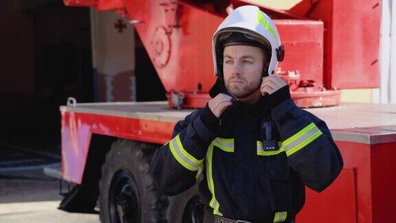 画像英俊的消防员在装备服装上戴上头盔看着相机