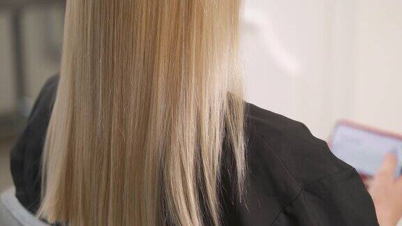 染过的金发的特写镜头沿着干头发慢慢地上下移动停在头发末端