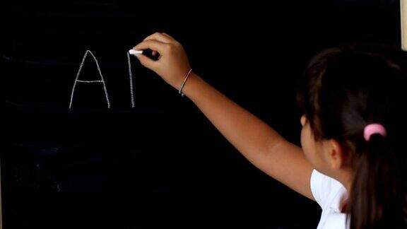 小女孩在黑板上写字母