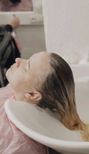 女发型师在给女人染完头发后给她洗头