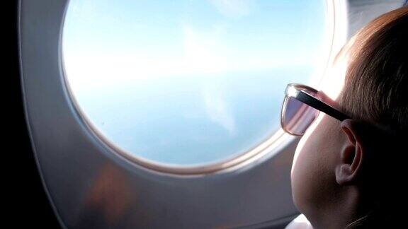 一个不知名的男孩戴着墨镜望着飞机窗外