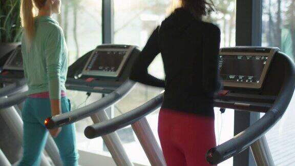 女孩们在健身馆的跑步机上跑步