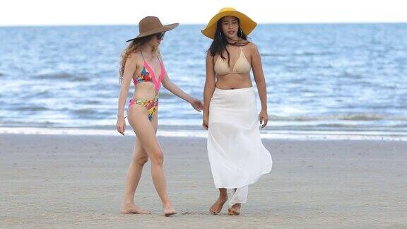 夏天穿着比基尼的女人和朋友在海滩上散步