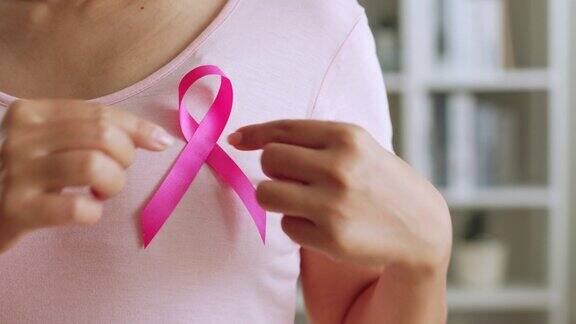 女性展示粉色丝带作为十月乳腺癌宣传月的标志