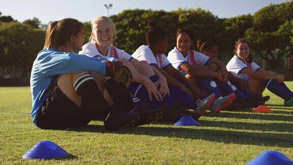 女足队员坐在地上聊天在足球场上4k