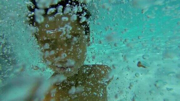 一个年轻的西班牙男孩在夏天跳进后院的游泳池
