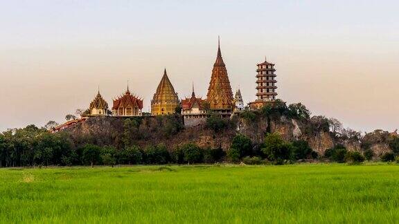 时间流逝的景观WatThamSua寺庙(老虎洞寺庙)在日落的场景茉莉稻田在北碧府泰国是每个人都必须参观的重要地标吗