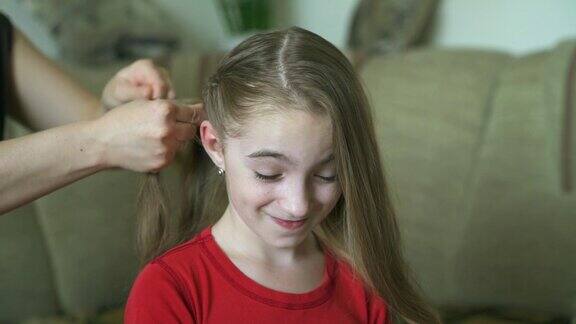 女人的手为她的小女儿做发型一位妇女正在为她的女儿编头发