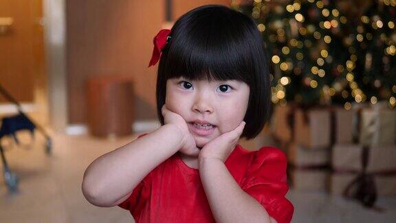 新年一个身穿红色连衣裙的韩国女孩站在圣诞树前
