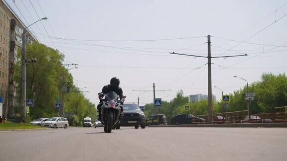 在城市里一名男子骑着摩托车沿着大马路和汽车行驶