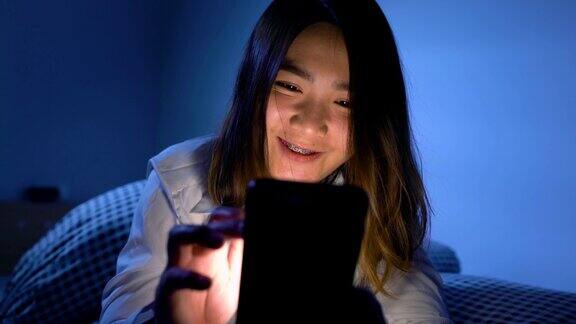 女人晚上在床上玩智能手机