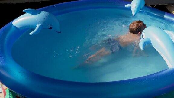 孤独的小男孩在自家后院玩充气游泳池