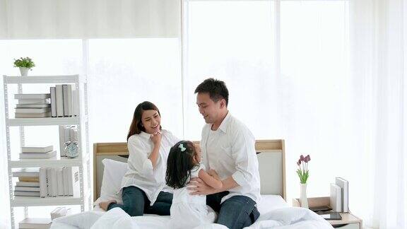 亚洲家庭一起在房子里度过的快乐时光三岁的爸爸、妈妈和女儿喜欢在床上玩耍