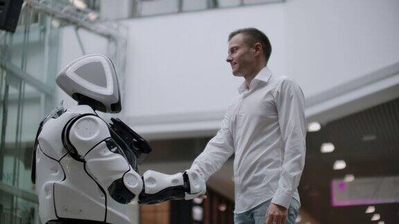 人与现代人工智能技术的互动走近科学家的男性手摇机械臂机器人和人类的手一起握手会见和问候朋友