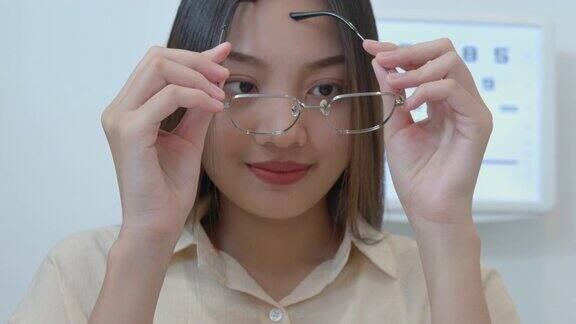 年轻的亚洲女人尝试新的眼镜在光学商店